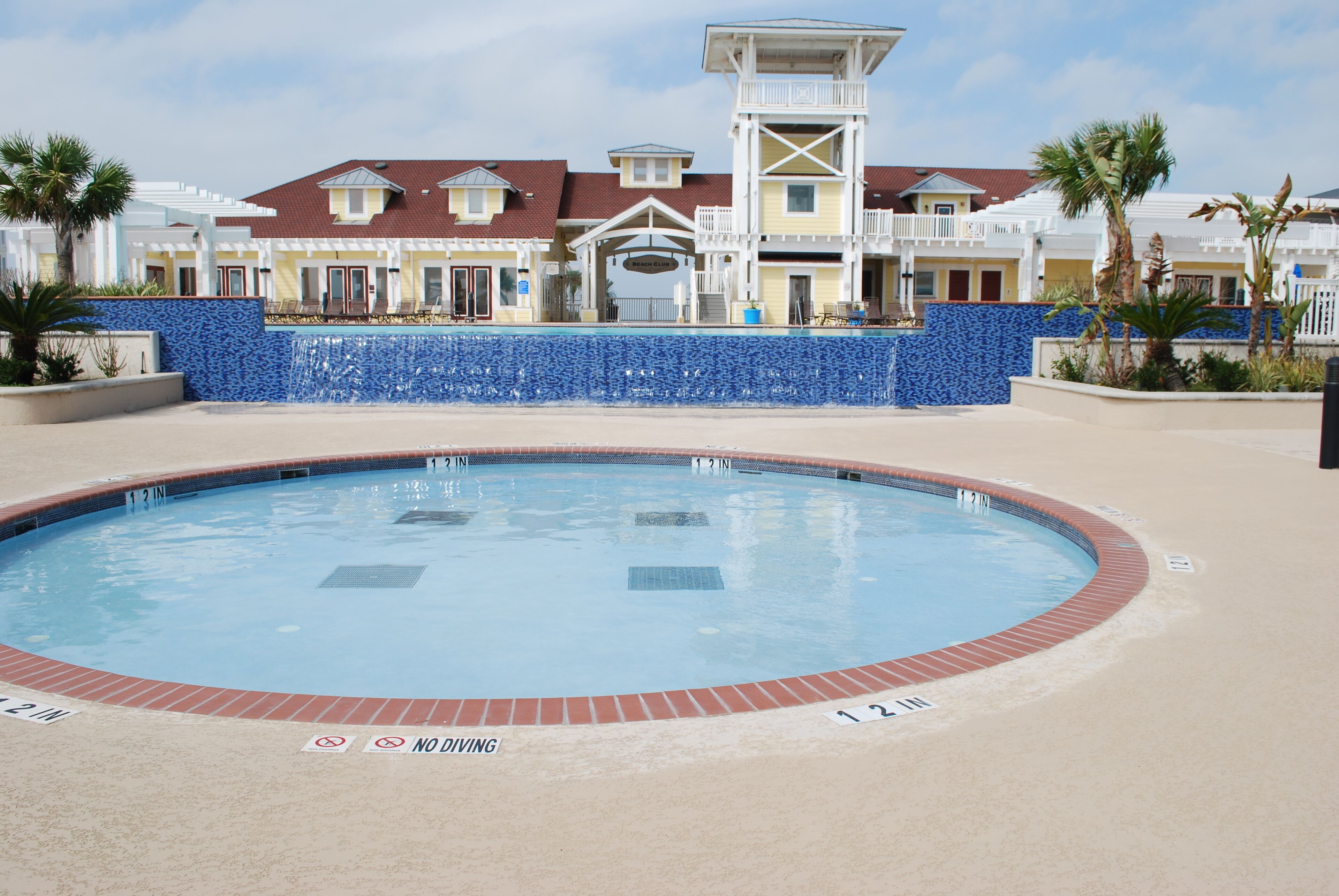 A swimming pool with a no diving sign, surrounded by a blue-tiled wall and a brick border.