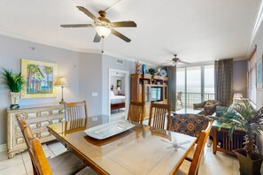 Relax in a spacious living room with a dining table, comfortable seating area, and large windows offering a view of the outdoors.