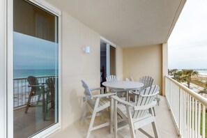 Enjoy the ocean view from this balcony with a table and chairs.
