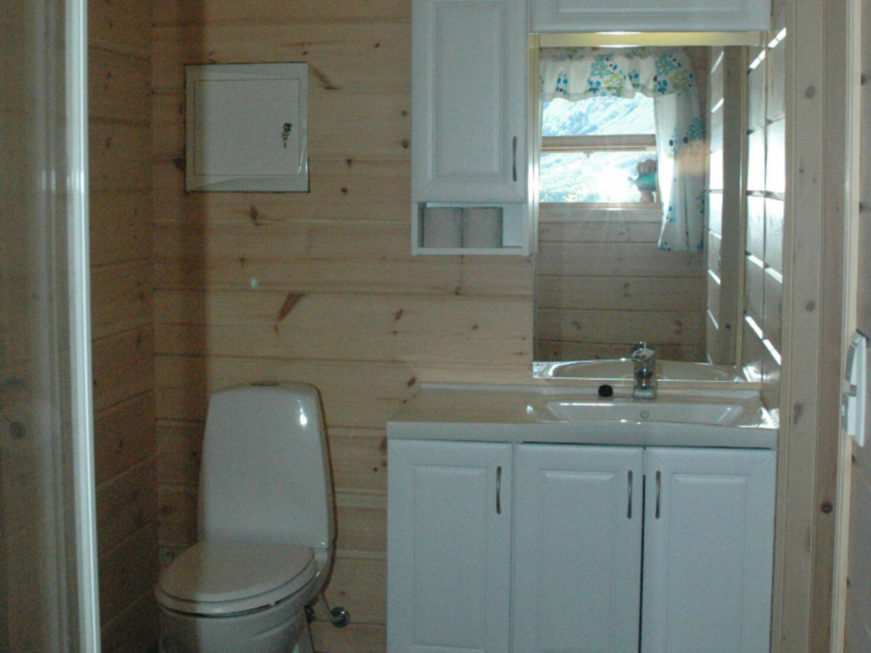 A small, compact bathroom with a toilet, sink, and mirror.