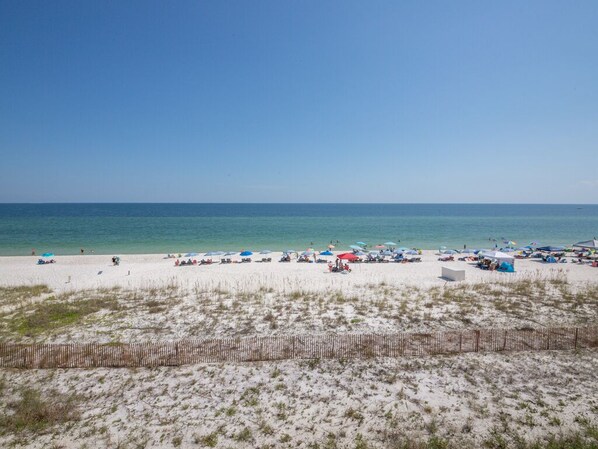Relax on the beach with comfortable sun loungers and umbrellas, surrounded by well-maintained dunes.