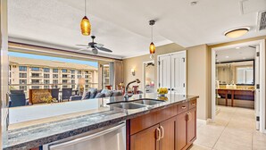 A modern kitchen with a large island, stainless steel appliances, and pendant lighting.