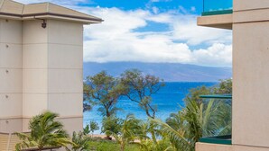 A view of a building with a balcony overlooking a beach and ocean.