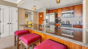 A kitchen with a central island, stainless steel appliances, and a colorful backsplash.