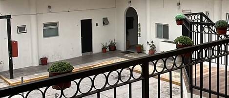 A multi-level courtyard with balconies, potted plants, and a wooden floor.
