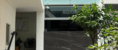 Un área de recepción con una escalera de baldosas que sube a un balcón con plantas en macetas.
