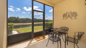 Une pièce dotée de grandes fenêtres donnant sur une rivière, une table avec des chaises et une fresque murale.