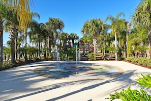 Stroll through a serene outdoor oasis surrounded by lush greenery and a tranquil water feature.