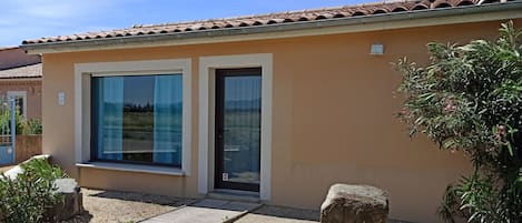 Un bâtiment moderne à la façade beige, doté de grandes fenêtres et d’un toit recouvert de tuiles.