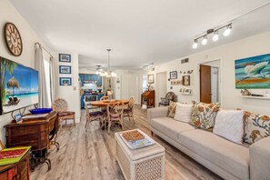 A spacious living room with a large sofa, a dining table, and a kitchen in the background.