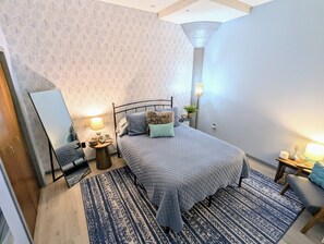 Une chambre à coucher avec un lit, des tables de chevet, un miroir et un tapis à motifs.