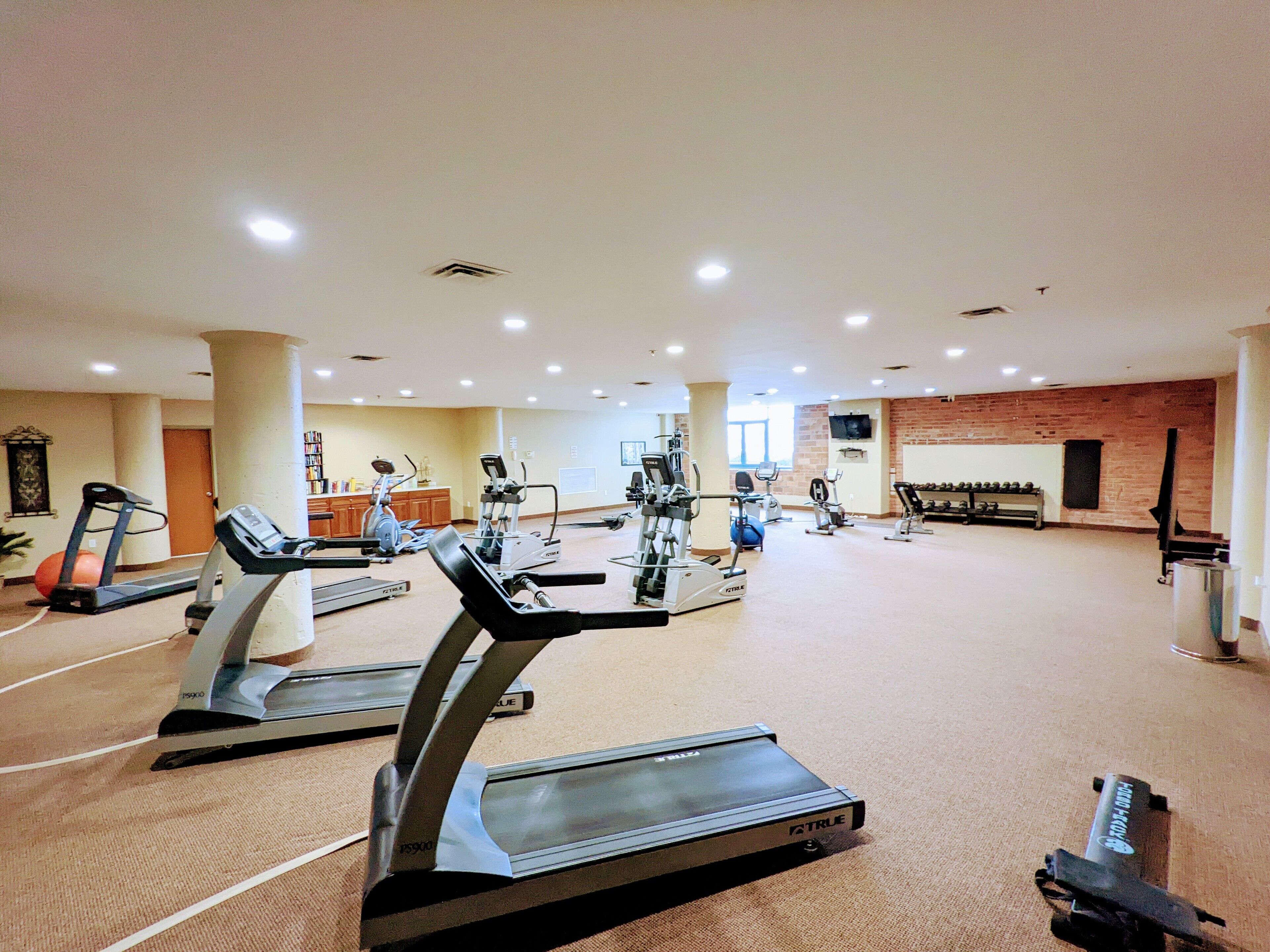 Une salle de sport spacieuse équipée de plusieurs tapis de course, de vélos d’appartement et d’autres appareils de musculation.