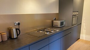 Una cocina moderna con estufa a gas, microondas y horno empotrado.