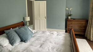 Un dormitorio con cama, cómoda, mesita de noche y una puerta.