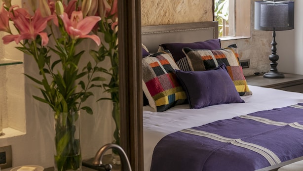 Ein modernes Hotelzimmer mit einem großen Bett, einem Badezimmer mit Marmorwaschbecken und einer Blumenvase.