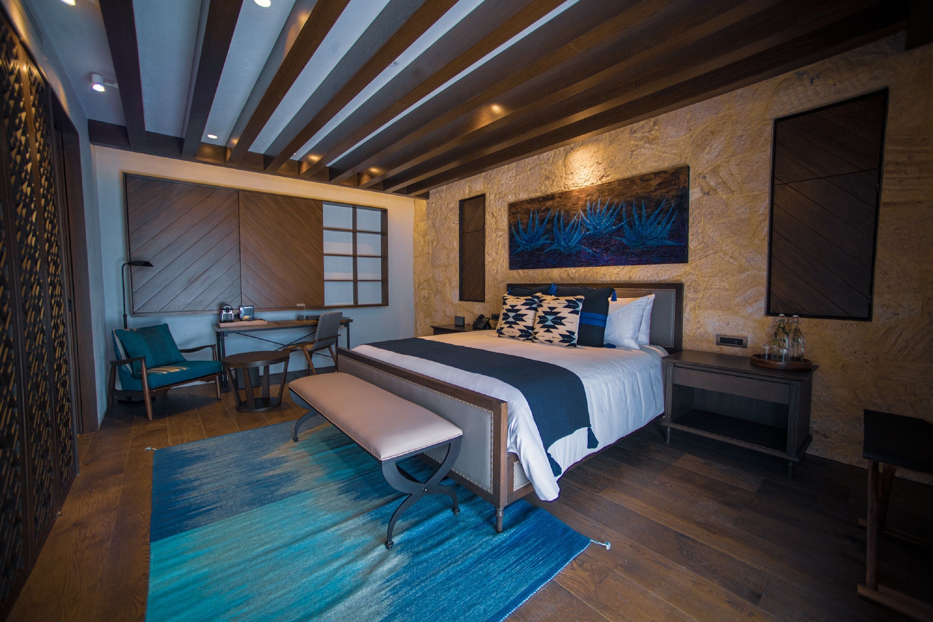 Un dormitorio moderno con cama, banco, escritorio y silla.