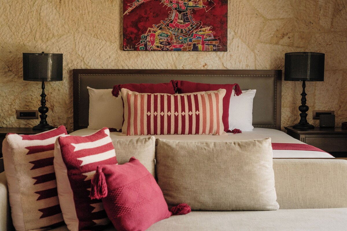 A hotel room with a large bed, two bedside lamps, and a colorful artwork on the wall.