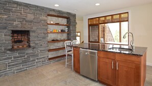 A kitchen with a stone wall, wooden shelves, a dishwasher, and a window with a view. - UNIQUE! 40 Pvt. Ac. Fireplace, Grill, Enclosed Heated Pool & Hot Tub (Saugerties)