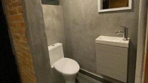 Et lille, kompakt badeværelse med toilet, håndvask og spejl.