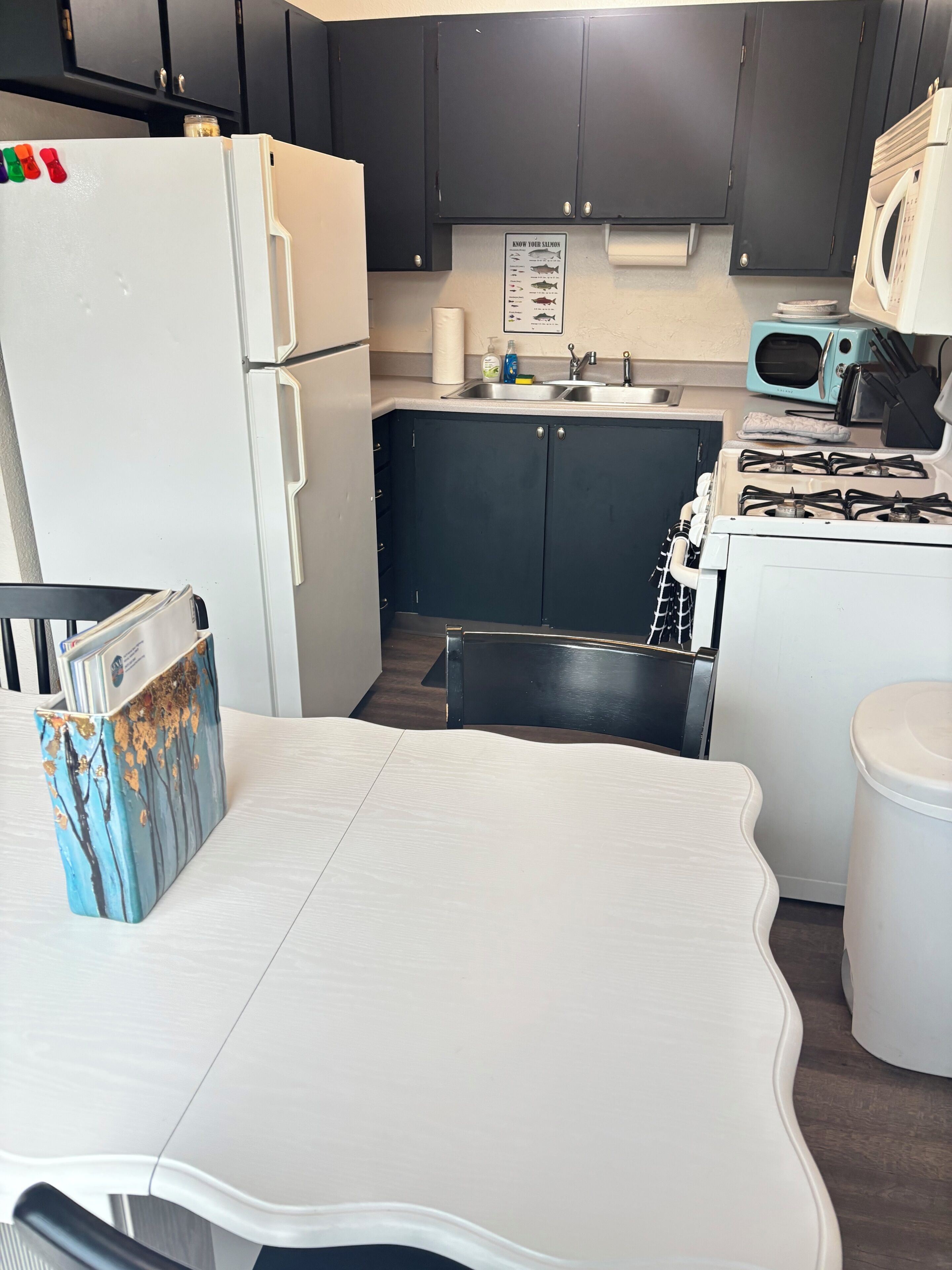 Eine kleine Küche mit Kühlschrank, Herd, Mikrowelle und Spüle.