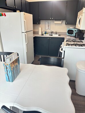 Eine kleine Küche mit Kühlschrank, Herd, Mikrowelle und Spüle.