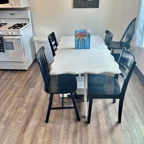 Una mesa de comedor con seis sillas, una caja de conservas y una estufa blanca al fondo.