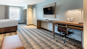 A hotel room with a bed, a desk with a chair, a flat-screen TV mounted on the wall, and a lamp on the desk. - MainStay Suites Durango (Durango)