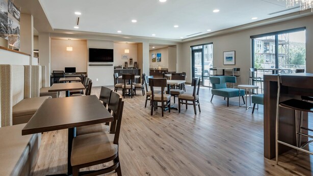 A spacious hotel lobby with multiple seating areas, a kitchen in the background, and large windows offering a view of the outside. - MainStay Suites Durango (Durango)