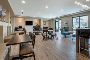 A spacious hotel lobby with multiple seating areas, a kitchen in the background, and large windows offering a view of the outside. - MainStay Suites Durango (Durango)
