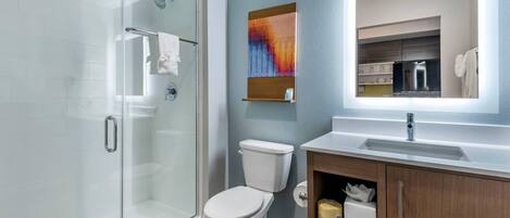 A modern bathroom with a glass shower enclosure, a white toilet, and a wooden vanity with a mirror.