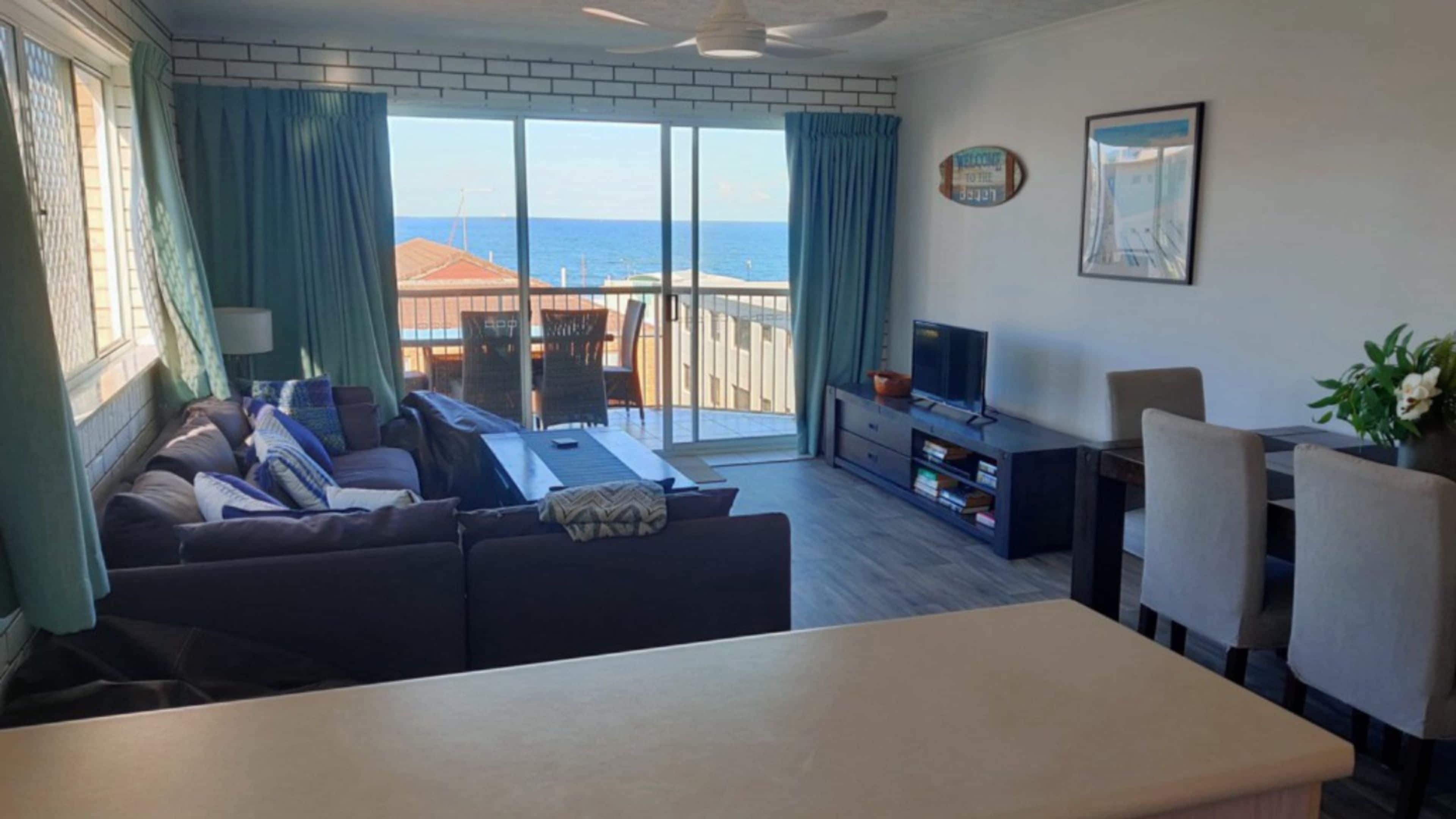 A living room with a sofa, TV, and dining area with chairs.