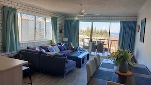 A living room with a sofa, a dining table, and a view of the sea. - Solaris Court U5 Steps To Kings Beach Ocean Views (KINGS BEACH)