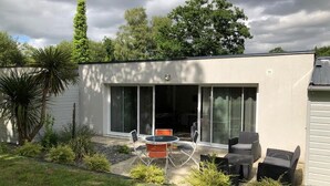 A modern house with a patio area featuring a round table and four chairs. - Les Cottages du golf 2/3 (LE TRONCHET)