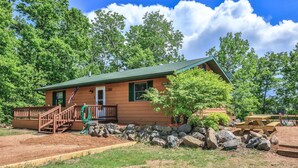 A cabin with a green roof, wooden exterior, and a porch with a bench. - God’s Country Minocqua, Wi. - “Up North” @ Back Bay Cabins on Lake Shishebogama  (Minocqua)