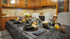 Uma sala de jantar com uma mesa posta para quatro pessoas, armários de madeira e painel de azulejos.
