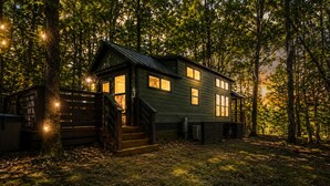 A cabin with a porch, surrounded by trees.