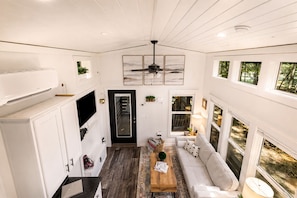A compact living space with a kitchenette, a sofa, a coffee table, and a ceiling fan.