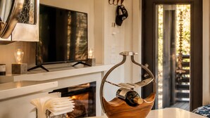 Uma cozinha moderna com lareira, um suporte para garrafas de vinho em formato de tigela de madeira e uma televisão sobre o balcão.