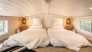 Quarto com duas camas, uma janela e um lustre.