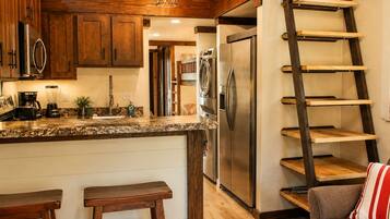 A kitchen with wooden cabinets, a stainless steel refrigerator, a coffee maker, and a blender on the counter.