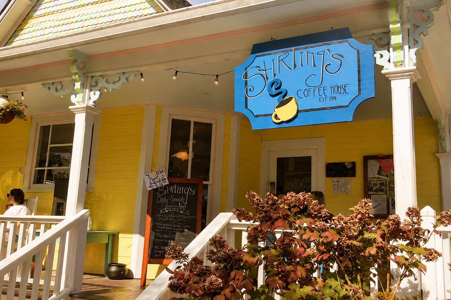 A yellow building with a blue sign reading 'Stirling's Coffee House' and a signboard listing daily specials.