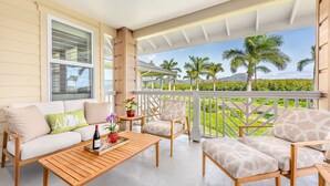 A covered outdoor seating area with a sofa, chairs, and a coffee table.