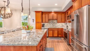 A modern kitchen with wooden cabinets, stainless steel appliances, and a marble island.