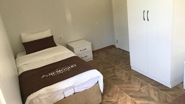 Un dormitorio con cama, mesita de noche, armario y suelo de baldosas.