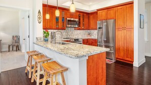 Una cocina moderna con armarios de madera, electrodomésticos de acero inoxidable y encimera de granito.