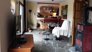 Un salon avec un téléviseur, une table à manger, un canapé et une cheminée.