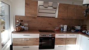 Une cuisine moderne avec des meubles en bois, un four encastré et une fenêtre qui laisse entrer la lumière naturelle.