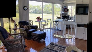 Un espacio de sala amplio con un ventanal grande, una mesa de comedor, una zona de cocina y un rincón de descanso acogedor.