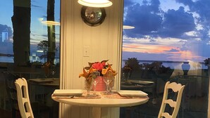 Un comedor con una mesa redonda, dos sillas, un jarrón con flores y una lámpara colgante.
