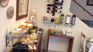 A breakfast buffet with various food items and a wine rack. - Pousada Mar Deny Campos (Campos do Jordão)